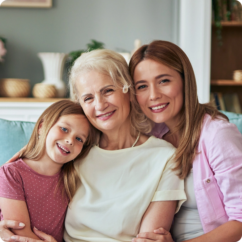 Three generations of women smiling together on a couch